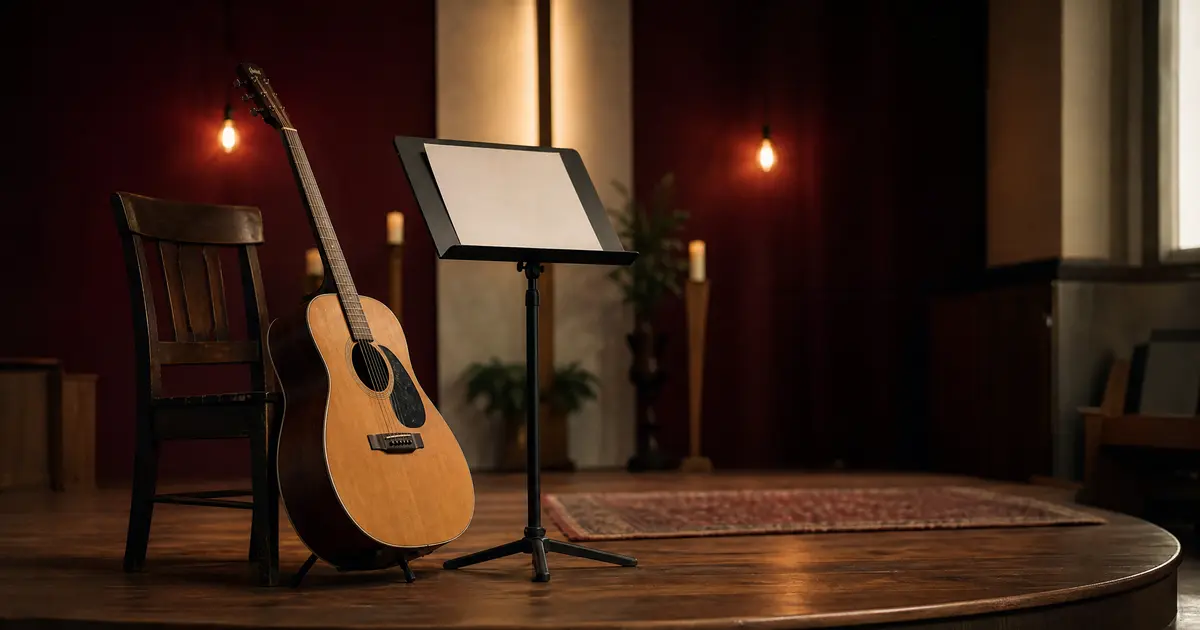 An acoustic guitar resting against a chair on a small church stage with a blank music stand in an empty room